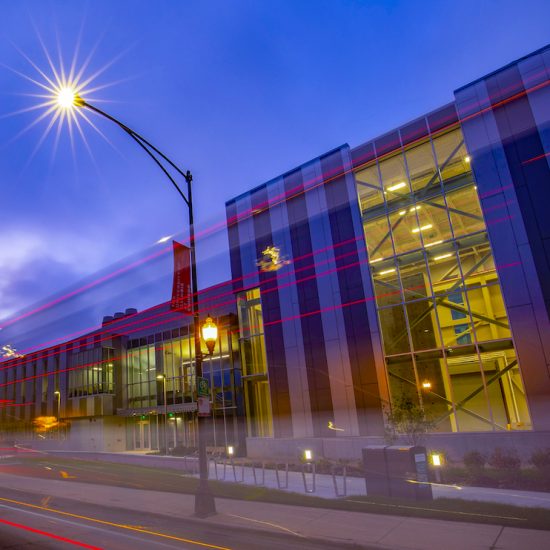 The Engineering Innovation Building at night, showing a glimpse of the High-Bay Structures Laboratory inside